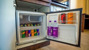 Un refrigerador abierto con bebidas y una botella de agua.