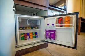 Un refrigerador abierto con bebidas y una botella de agua.