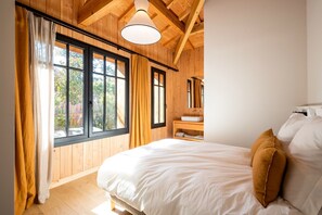Una camera da letto con un letto grande, pareti in legno, una finestra con tende e una lampada a soffitto.
