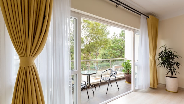 A balcony with a table and chairs, a potted plant, and a view of trees and a building. - Casa Misa Westlands (Nairobi)