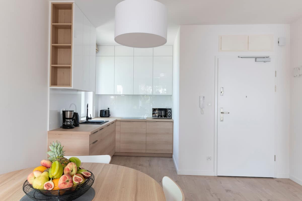 Una cocina moderna con armarios de madera, una puerta blanca y un frutero sobre la mesa.