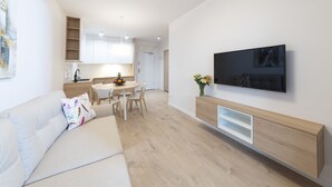 Un salon moderne comprenant un canapé, un téléviseur et un coin repas avec des chaises et une table.
