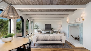 Una sala de estar moderna con chimenea, un comedor con mesa y sillas, y ventanas amplias que ofrecen vistas al exterior.