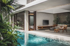 A modern living room with a pool, wooden furniture, and a flat-screen TV. - Blossom Eco Luxe Villas by Ekosistem (Canggu)