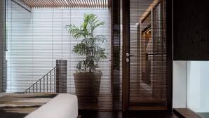 Een moderne slaapkamer met een bed, een kamerplant en een schuifdeur.