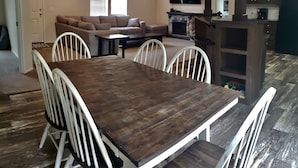 A dining area with a wooden table and white chairs, a living room with a sofa and TV, and a kitchen with a coffee maker. - Secluded in the woods. No neighbors in sight. (Pullman)