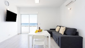 Una sala de estar moderna con una mesa blanca, un sofá gris y un televisor montado en la pared.