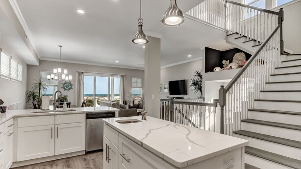 A modern kitchen with a large island, white cabinetry, and a view to the outside. - Pet friendly, newly renovated, ocean and beachfront historical home (Fernandina Beach)