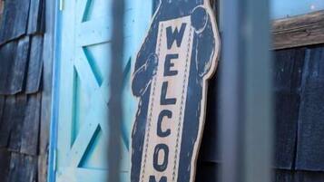 Une porte en bois ornée d’un motif géométrique bleu et d’une enseigne en forme d’ours sur laquelle on peut lire « BIENVENUE ».