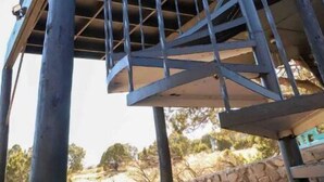 Une structure d’escalier en colimaçon avec des rampes en métal et un design incurvé, soutenue par des poutres verticales.
