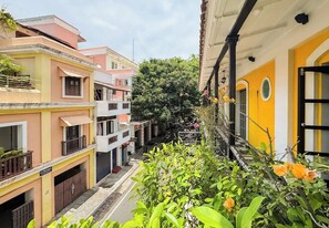 A narrow street with multi-story buildings, balconies, and lush greenery. - Le Chateau (Puducherry)