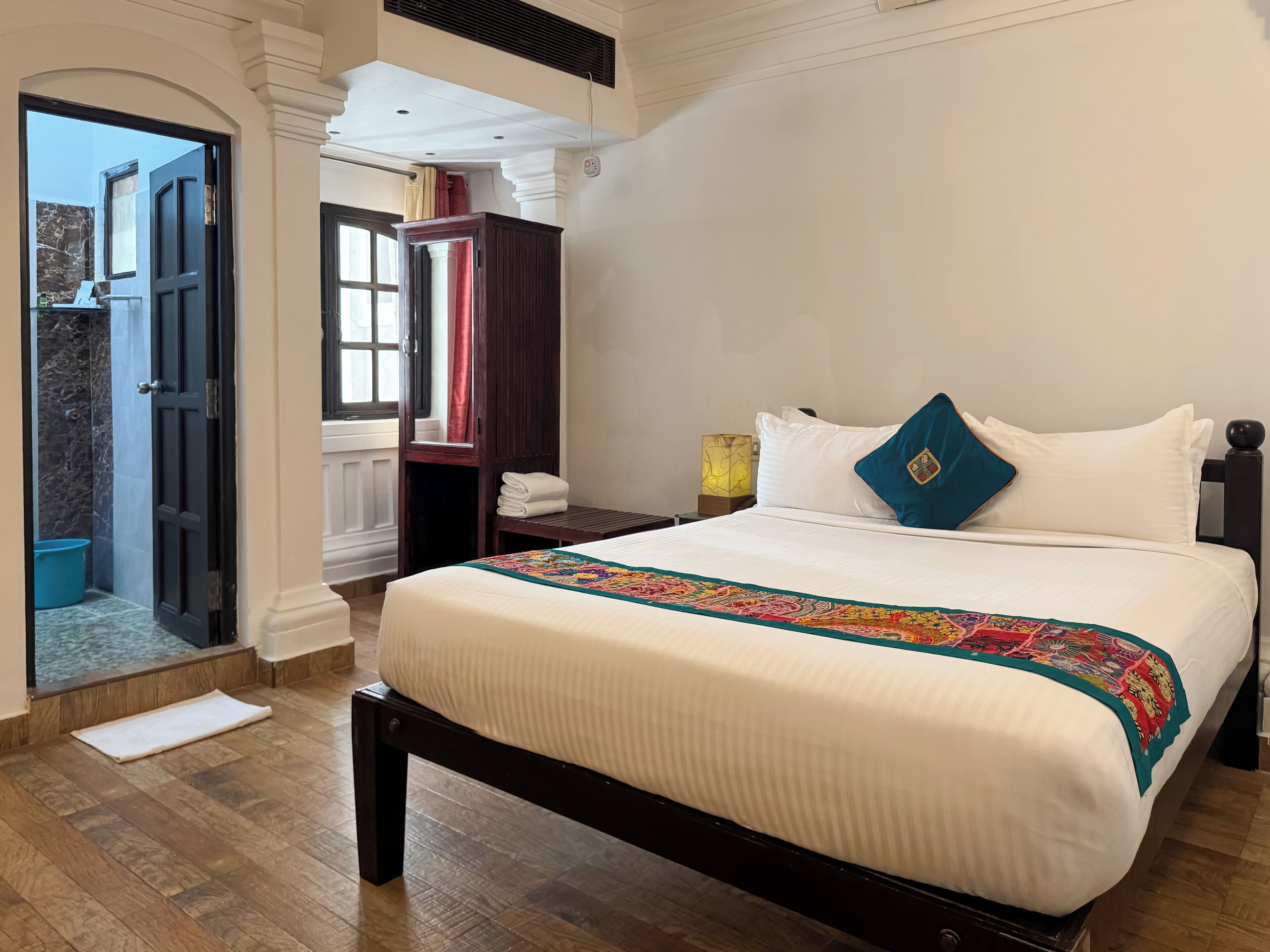 Ein Hotelzimmer mit einem großen Bett, Holzboden, einem Kleiderschrank und Blick auf einen Pool.