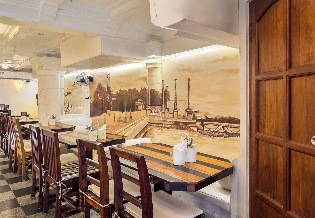A restaurant with wooden tables and chairs, a mural of a cityscape, and a wooden door.