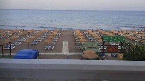 Ein Strand mit Reihen von Liegestühlen und Sonnenschirmen, einem Schild mit der Aufschrift 'Playa Hermosa' und dem Meer im Hintergrund.