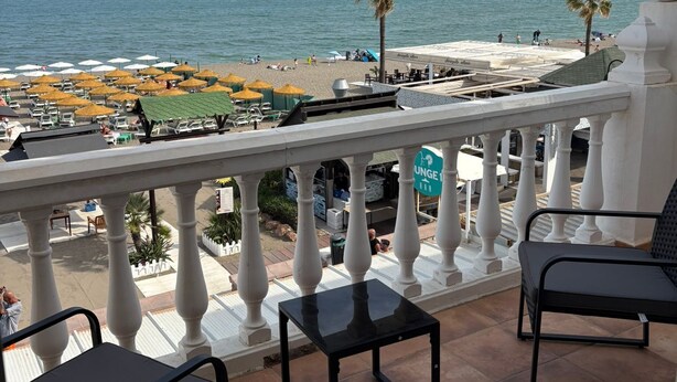 Ein Balkon mit Blick auf den Strand, weißen Brüstungen und einem Schild für die Lounge Bar.