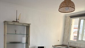 Eine kleine Küche mit Esstisch, Stühlen, einer Mikrowelle und einer Hängelampe.