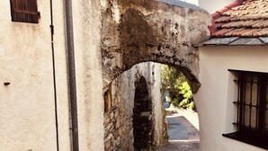 A narrow stone pathway leading through an old stone archway, flanked by buildings with traditional architecture. - Piccola Navetta (Diano San Pietro)