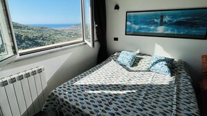 A bedroom with a bed, a window, and a painting of a lighthouse. - Piccola Navetta (Diano San Pietro)