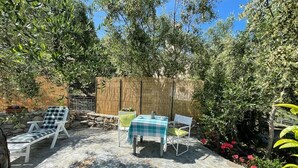 An outdoor patio with stone flooring, a table with a checkered tablecloth, and two chairs. - Piccola Navetta (Diano San Pietro)