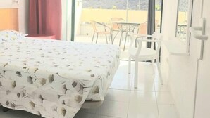 Ein Hotelzimmer mit Bett, einem Balkon mit Stühlen und Blick auf Berge.