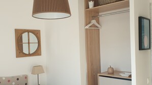 A bedroom with a bed, a hanging lamp, a dresser, a mirror, and a wall-mounted shelf. - Les Plus Hautes Falaises d' Europe (Criel-sur-Mer)