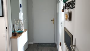 A hallway with a white door, a wooden chair, a white cabinet, and a wall-mounted shelf with decorative items. - Les Plus Hautes Falaises d' Europe (Criel-sur-Mer)