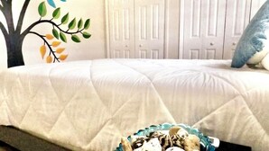 Un dormitorio con una cama, un mural en la pared y un cesto de objetos decorativos.