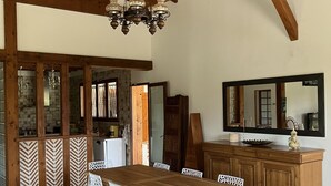 A dining area with a wooden table and white chairs, a chandelier, and a wooden cabinet with a mirror. - Villa Amandelle - for 6 to 8 persons (Moliets-et-Maa)
