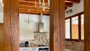 A kitchen with wooden beams, a chandelier, and a modern stove. - Villa Amandelle - for 6 to 8 persons (Moliets-et-Maa)