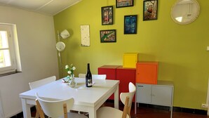 A dining area with a white table and chairs, a vase with flowers, and a bottle of wine. There are colorful cabinets and a mirror on the wall. - Very quiet 2 br apartment - Pool, private backyard - close to beaches (La Garde)
