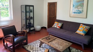 A living room with a purple sofa, a wooden coffee table, a black chair, a glass cabinet, and a door. - Very quiet 2 br apartment - Pool, private backyard - close to beaches (La Garde)