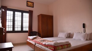 Un dormitorio con cama, armario, escritorio y ventana con cortinas.