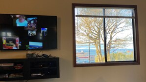 A television mounted on a wall with a window beside it. - Quaint Downtown Cottage (Astoria)