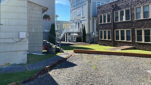 A residential area with houses, a gravel driveway, and a small garden area. - Quaint Downtown Cottage (Astoria)