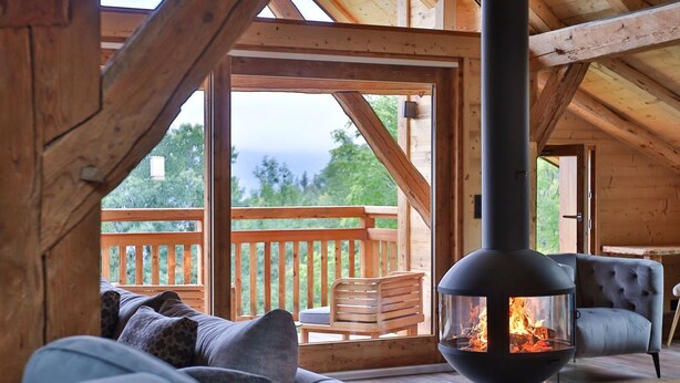 Un chalet confortable avec une cheminée, une terrasse en bois et une vue sur les montagnes.