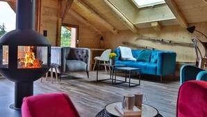 Une chaleureuse cabane en bois avec une cheminée, un canapé bleu et un fauteuil rouge.