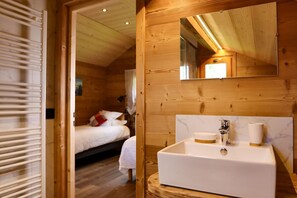 Een houten cabin met een wit wastafel, spiegel en houten vloer.