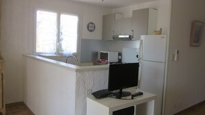 A compact kitchen with a microwave, refrigerator, and a small window.