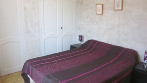 A bedroom with a bed, a nightstand, a lamp, and a door.