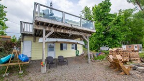 Une maison à deux étages dotée d’un balcon en verre, d’une terrasse en bois et d’une allée gravillonnée.