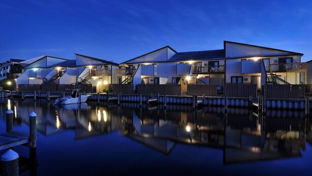 A waterfront property with multiple buildings, each featuring balconies and a reflective water surface. - Perfect Family Beach Stay • Private Courtyard • Walk Everywhere (Ocean City)
