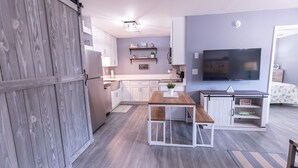 A modern kitchen with white cabinets, a wooden table, and a built-in TV. - Perfect Family Beach Stay • Private Courtyard • Walk Everywhere (Ocean City)