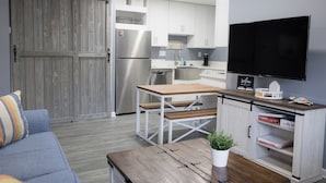 A compact living space with a kitchenette, a dining area, and a TV mounted on the wall. - Perfect Family Beach Stay • Private Courtyard • Walk Everywhere (Ocean City)