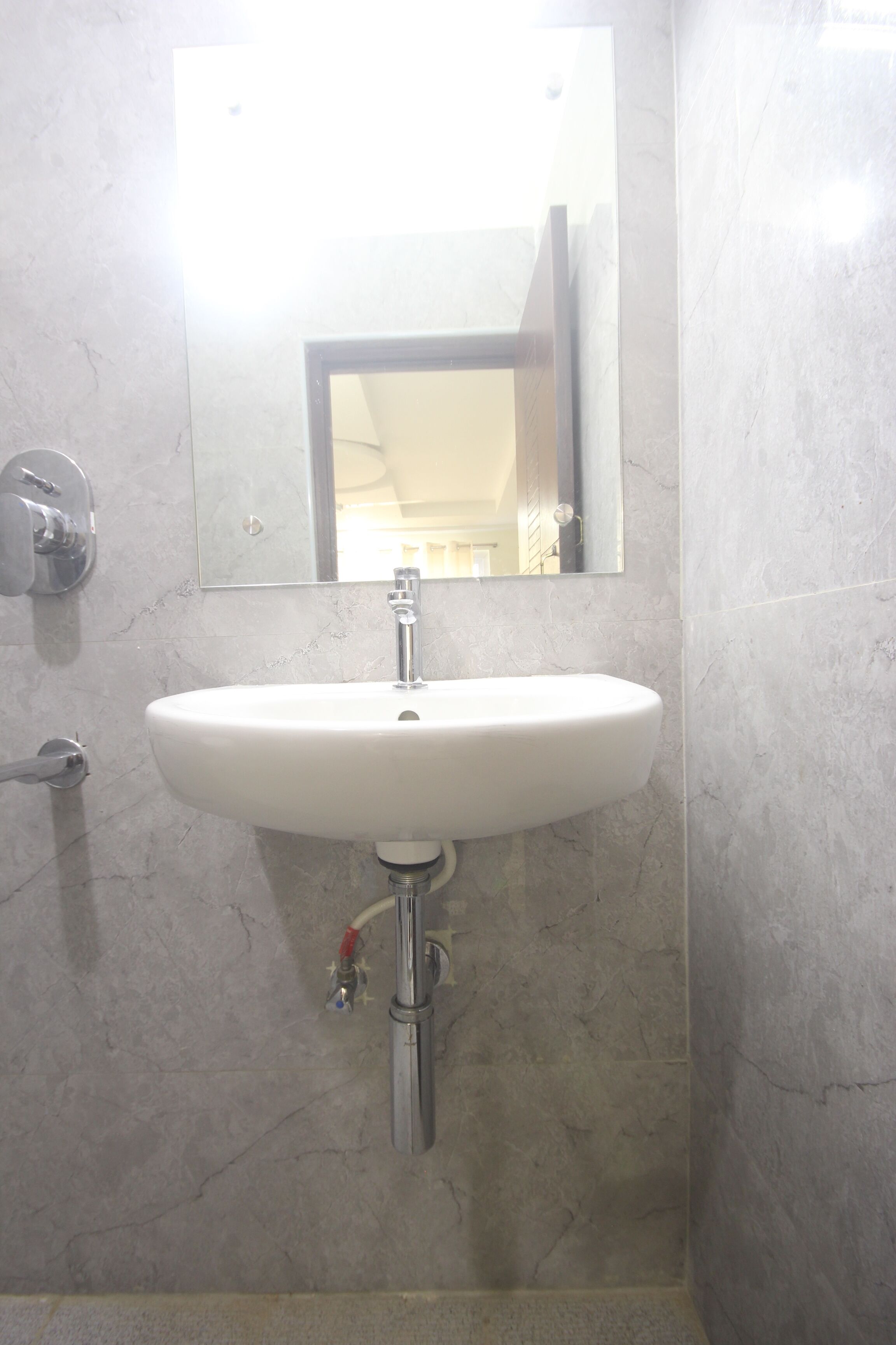 Une salle de bain avec un lavabo blanc, un miroir au-dessus et un porte-serviettes à gauche.