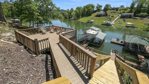 A wooden deck with a view of a lake, boats, and a small dock area.