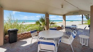 A covered outdoor seating area with a view of the beach. - Renovated Beach Paradise. Ground Floor unit 64 (Longboat Key)