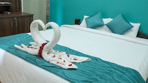 Uma cama com colcha verde-água, roupa de cama branca e almofadas verde-água.