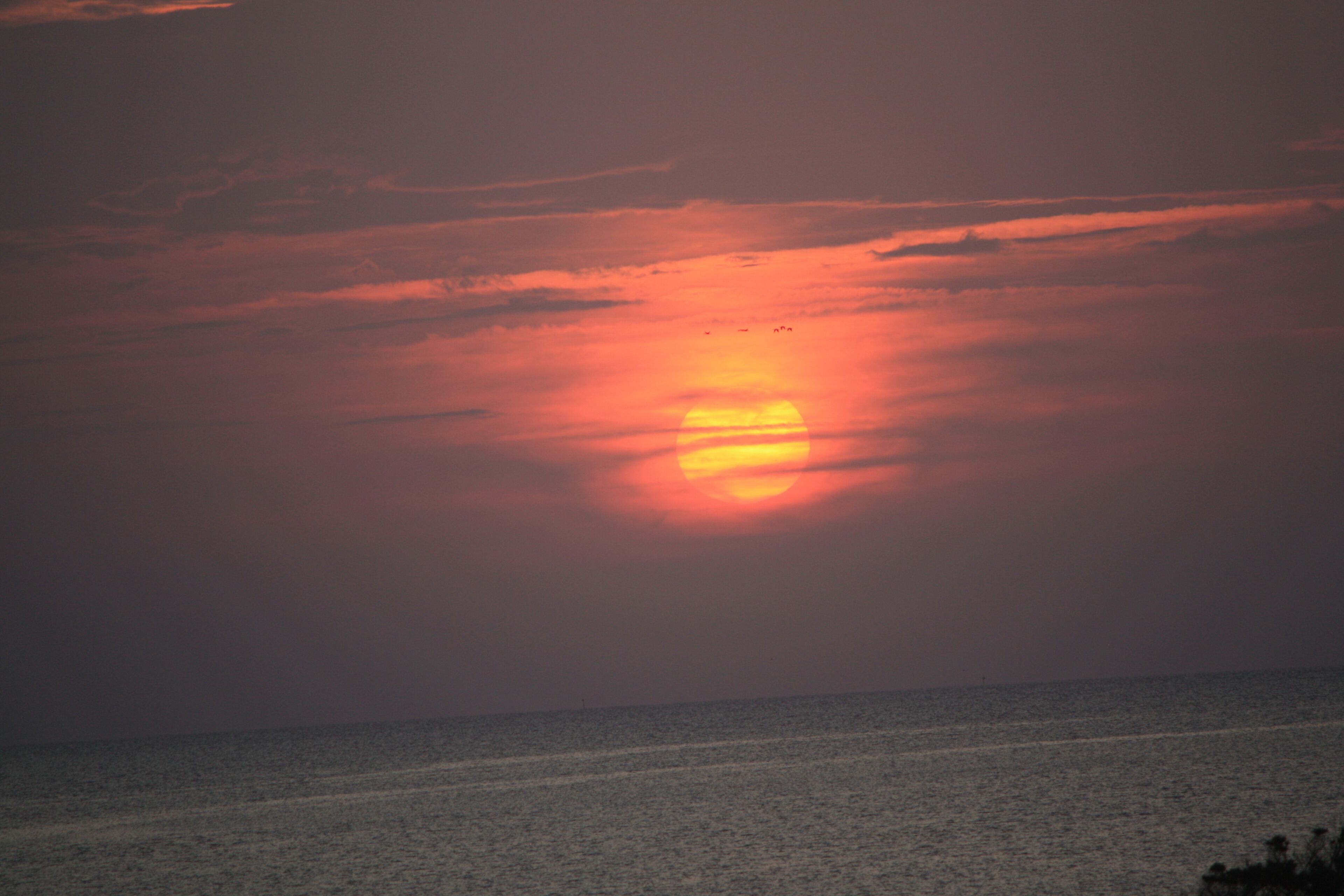 A sunset over a calm sea with a clear horizon.