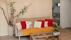A living room with a sofa, a coffee table, and two potted plants. - Appartement Nature et Jardin (Eymoutiers)