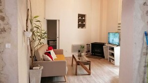 A living room with a sofa, coffee table, and a television. - Appartement Nature et Jardin (Eymoutiers)